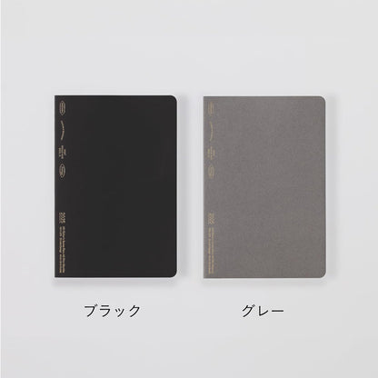 Two notebooks, one black and one gray, on a light gray background.