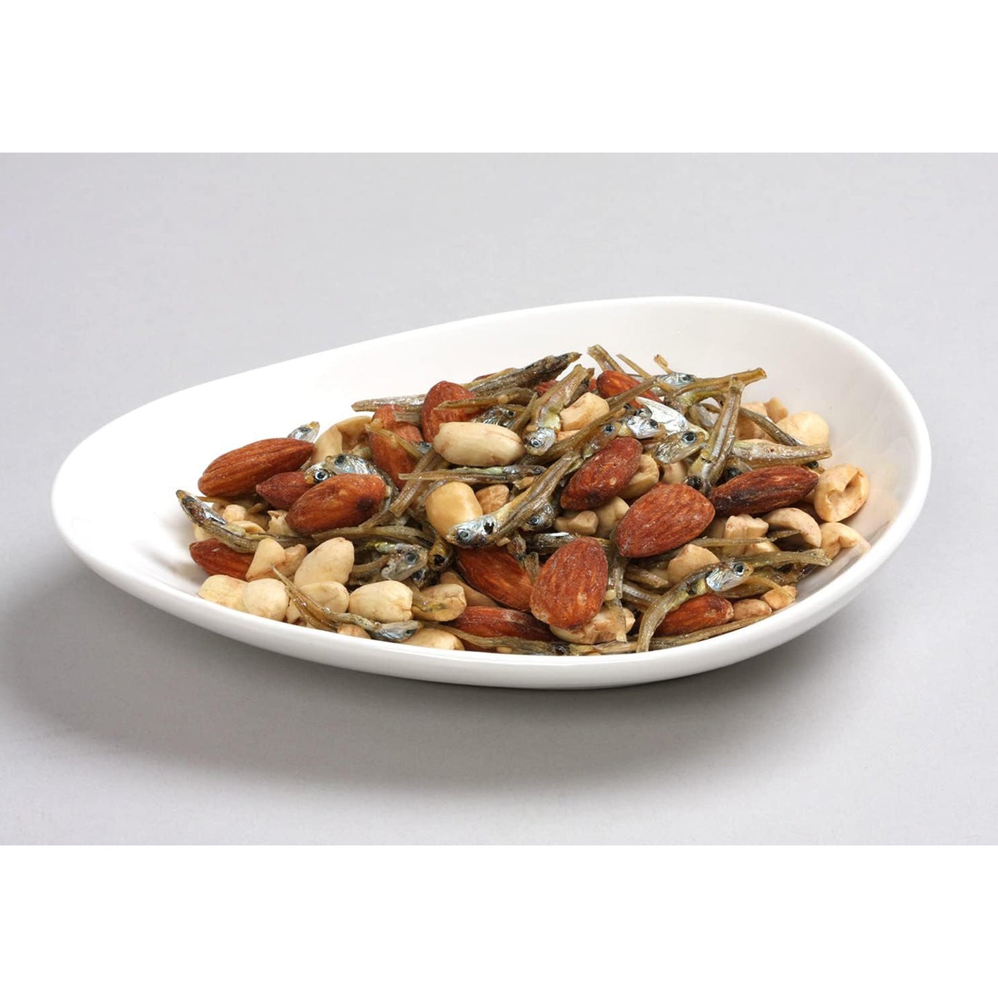 Assorted nuts and seeds on a white plate with a light gray background