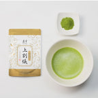 Matcha green tea packaging, bowl of matcha, and scoop of matcha on a white background
