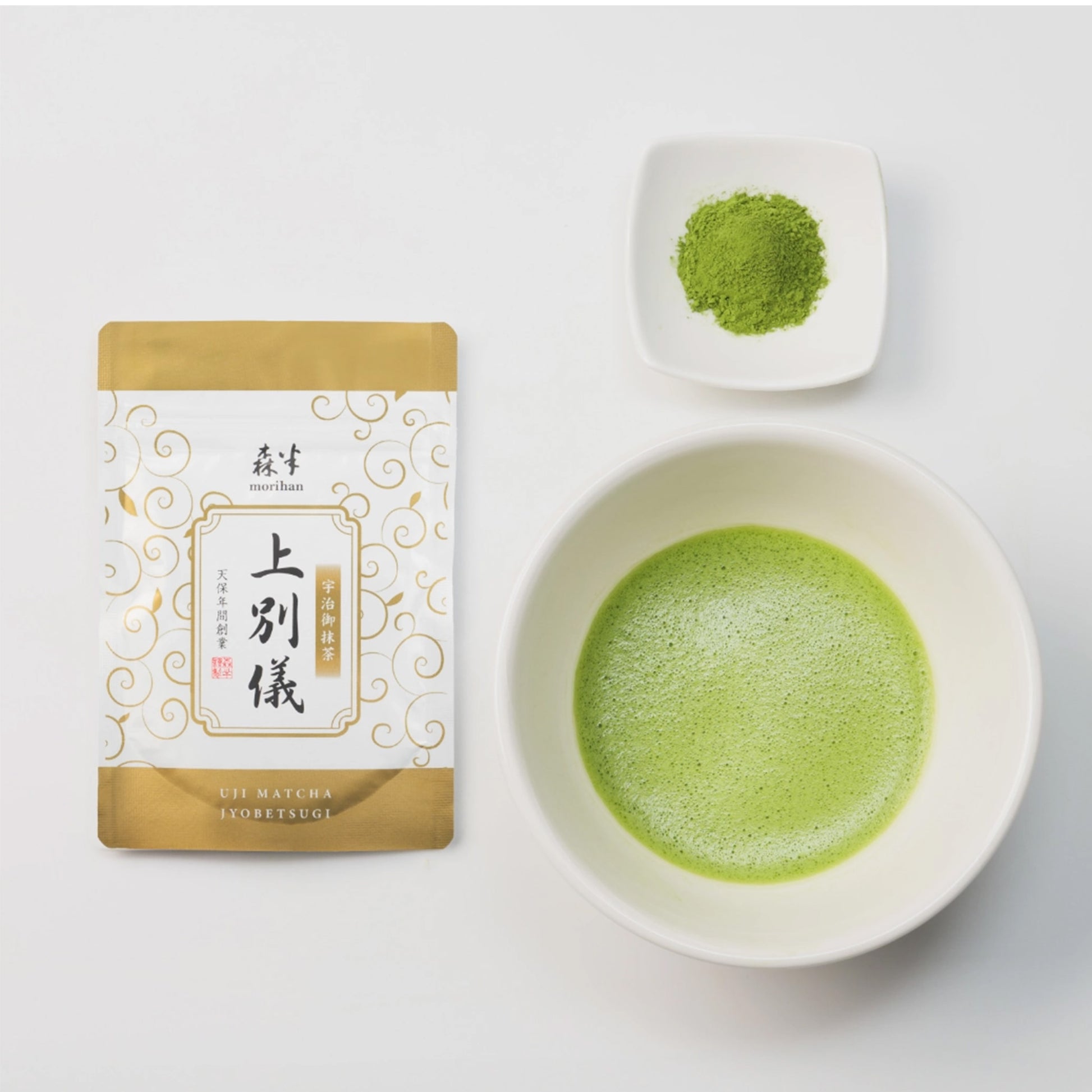 Matcha green tea packaging, bowl of matcha, and scoop of matcha on a white background