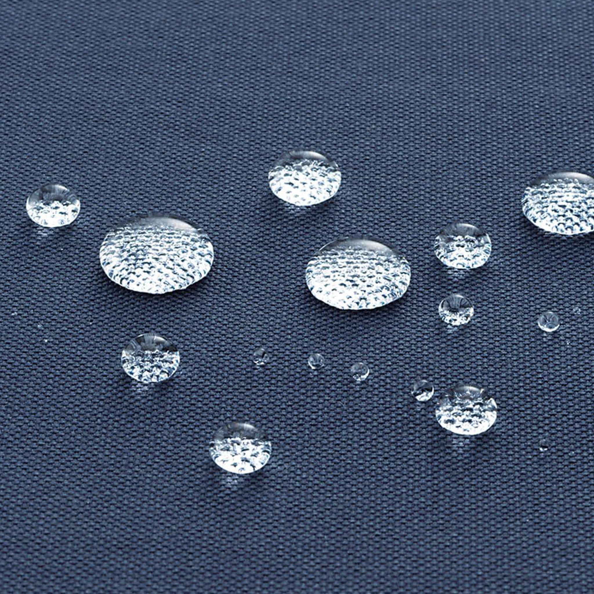 Clear, transparent oval gemstone cabochons with a textured, diamond-like surface arranged on a dark navy blue fabric background to demonstrate water repellency.
