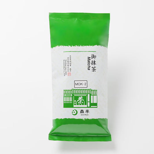 Green and white package of Mok-2 matcha powder on a white background